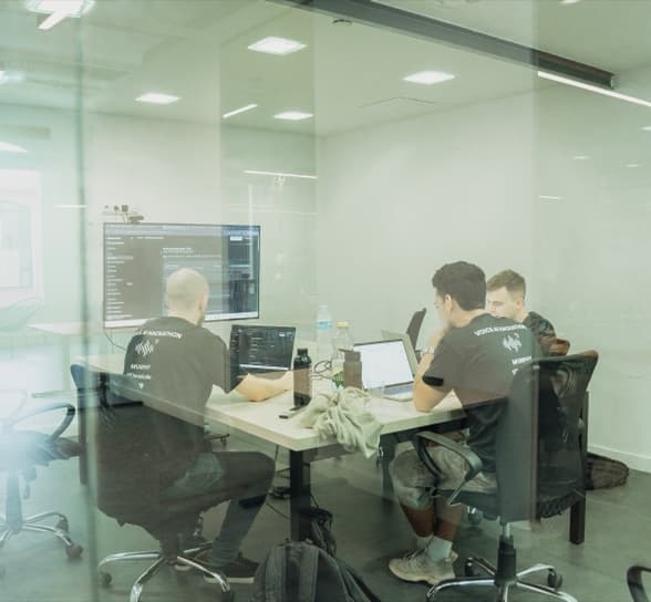 The team at work behind a glass wall, screens up